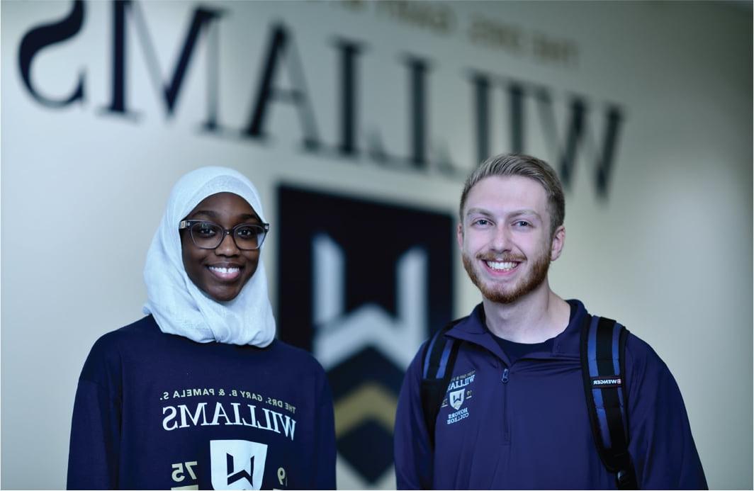 Two students standing inside Williams Honor College Building.